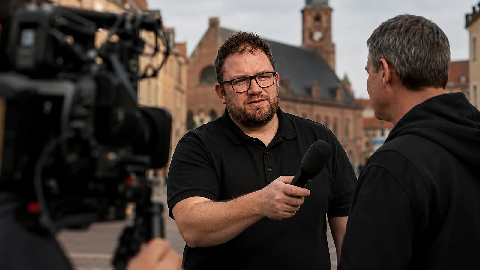 Adrian Oeschger bei einem Interview auf einem historischen Stadtplatz